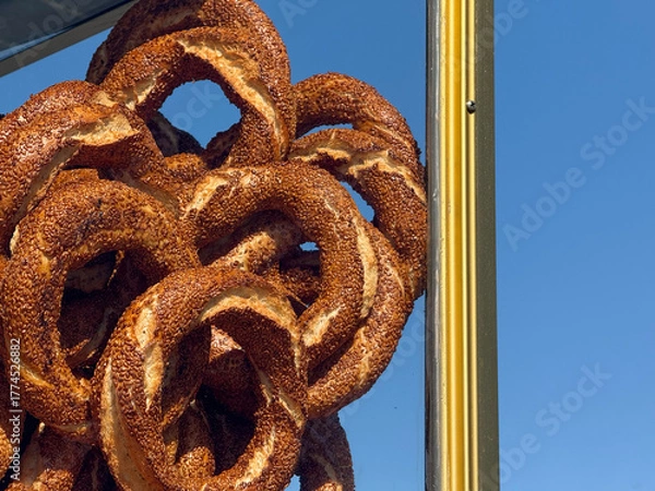 Obraz Fresh simit bagels stacked on a street stand under blue sky