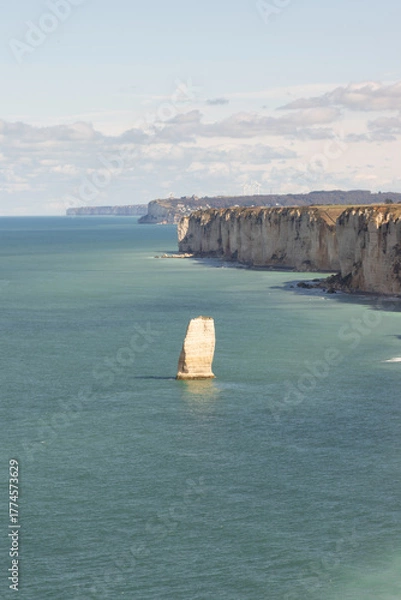 Fototapeta Lone white limestone rock formation rising from turquoise sea near Étretat, Normandy. Peaceful coastal scene showcasing the beauty of erosion and marine nature.