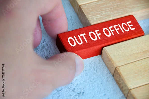 Obraz Hand pulling out a red wooden block with out of office text on. Getaway or on a vacation concept.
