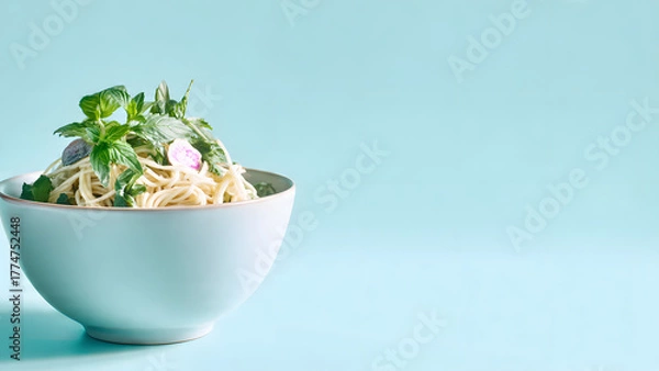 Fototapeta A simple close-up shot of a light-toned bowl containing noodles, vegetables, and herbs, set against a gentle pastel blue background. The clean and modern composition highlights simplicity, harmony, an