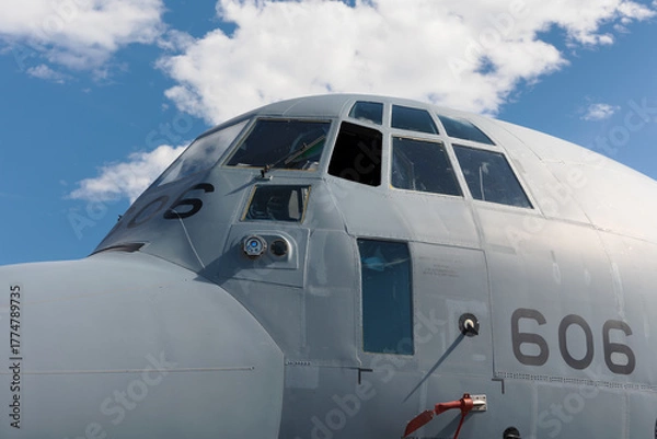 Fototapeta Detail of gray military transport airplane and plane. Cockpit and blue sky. Aircraft belonging to air force. Old retro design of cockpit.