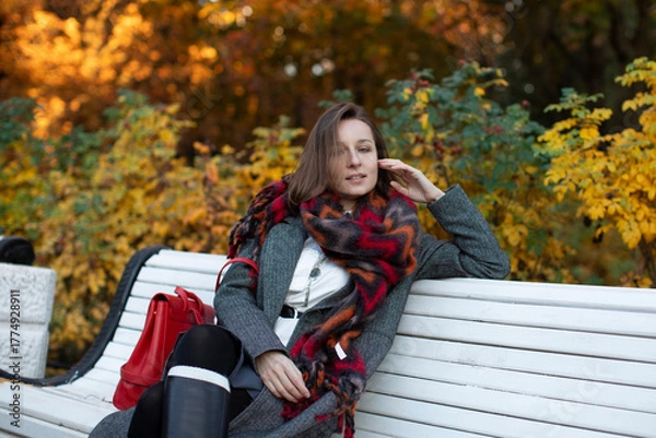 Obraz Beautiful business woman in a cozy scarf on an autumn park bench