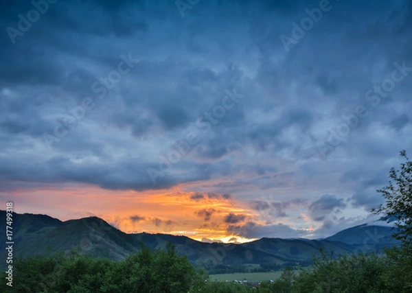 Fototapeta Beautiful dramatic sunset in the mountains. Landscape with sun light shining through orange clouds