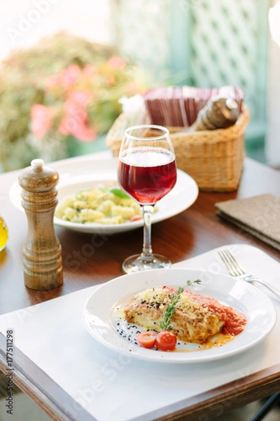 Fototapeta Italian food - delicious lasagne in white plate on table with red wine.