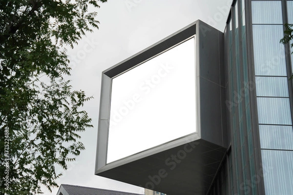 Fototapeta A mockup of a blank white billboard framed by a modern building facade, ideal for advertising
