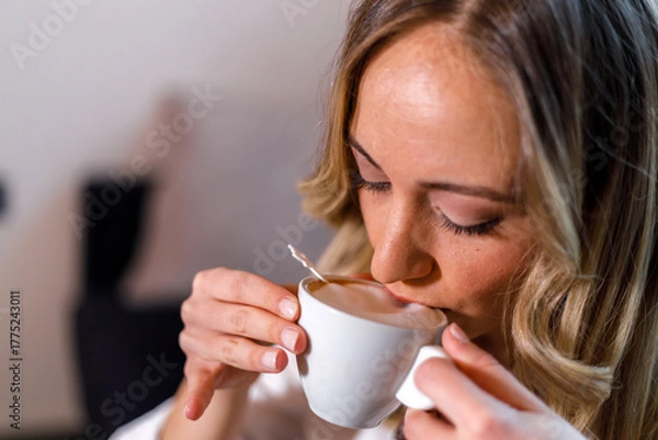 Fototapeta Woman enjoying a warm cup of tea in a cozy indoor setting during afternoon hours