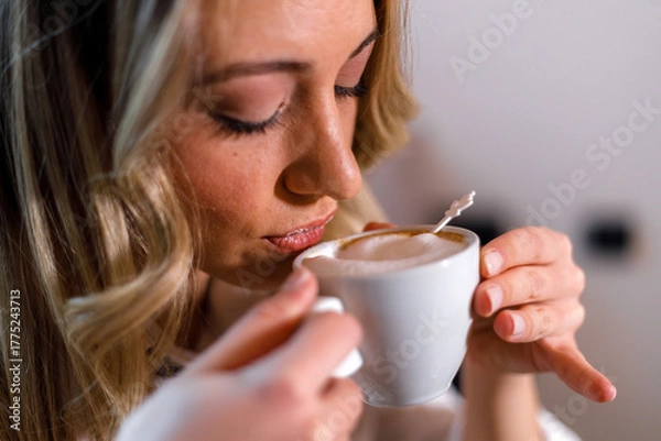 Fototapeta Woman enjoying a warm cup of coffee in a cozy setting while savoring the aroma