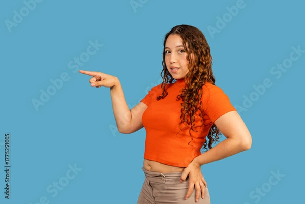 Obraz Woman pointing index finger away on blue background