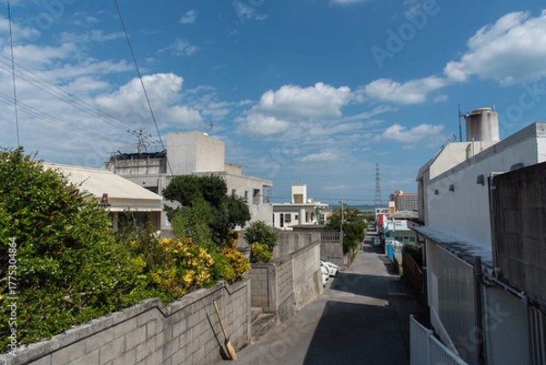 Obraz 遠くに海の見える晴れて緩やかな坂の路上に建物の影が出来た田舎の路地裏の道