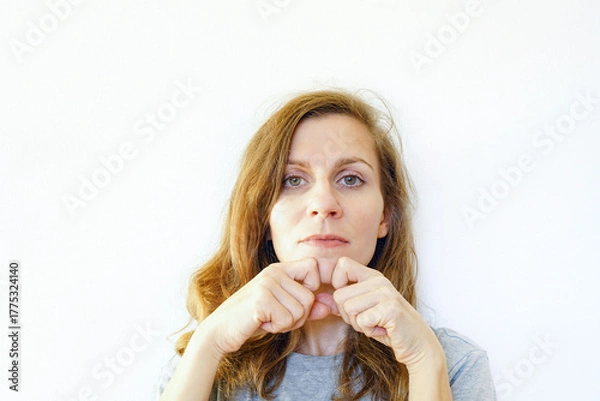 Fototapeta A woman performs a facial massage using her hands. Concepts of collagen stimulation, holistic skincare approach, natural beauty protocol, puffiness reduction method, and minimalist home treatment. 