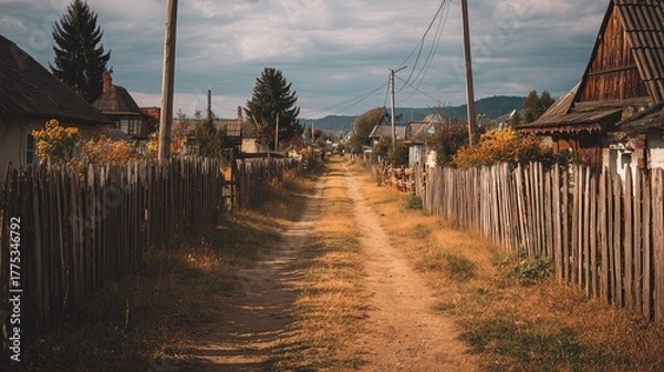 Fototapeta Dirt path through a rural village in a scenic landscape on a cloudy day