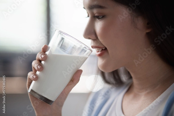 Fototapeta A close-up of a woman holding a glass of milk, showcasing the health benefits and simplicity of enjoying a refreshing, nutritious drink at home. Daily drink product health food lifestyle concept.