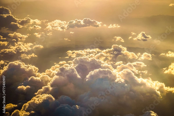 Fototapeta Golden sunset clouds viewed from airplane window, warm glowing sunlight, dramatic sky, soft texture, minimalistic aerial composition, peaceful atmosphere, travel and freedom feeling, dreamy light, nat