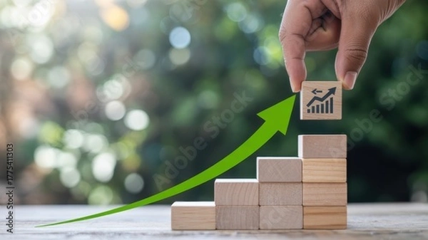 Obraz Hand placing wooden block with growth chart on stacked blocks symbolizing financial progress