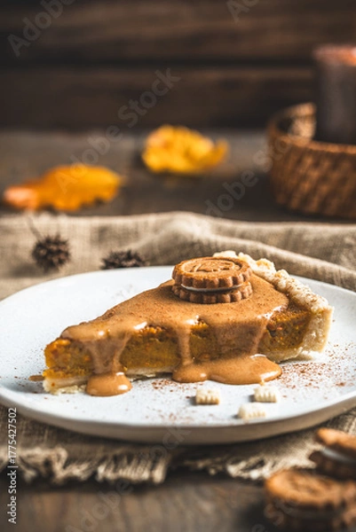 Fototapeta Piece of pumpkin pie with caramel sauce and cookie on a wooden table