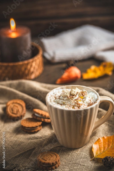 Fototapeta Moody, cozy autumn composition with a cup of coffee or hot chocolate with cream, candle and creamy colors