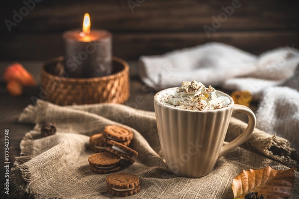 Fototapeta Moody, cozy autumn composition with a cup of coffee or hot chocolate with cream, candle and creamy colors