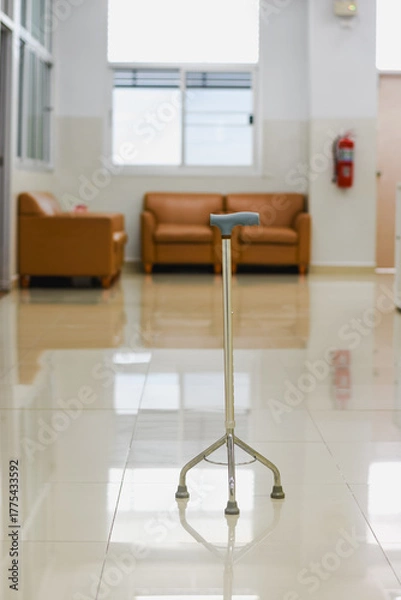 Fototapeta Four-legged walking cane with a blue handle against a white wall.