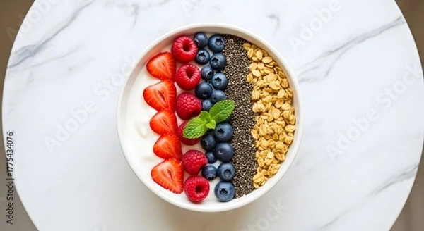 Fototapeta Aerial view of a bowl with yogurt, strawberries, blueberries, raspberries, chia seeds and granola