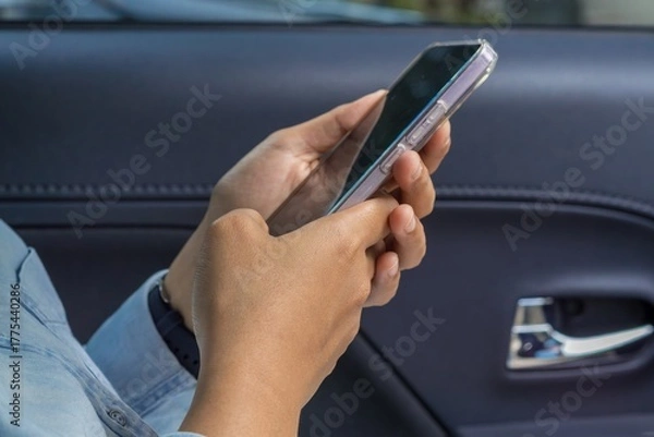 Fototapeta Close up of female hands holding a smartphone in car