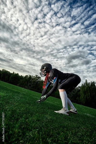 Obraz Woman American football player took up a position on the field against the sky.