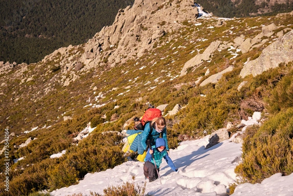 Obraz Mother and son climbing a mountain, walking across a snowfield