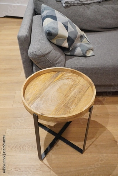 Obraz Wooden Round Coffee Table with Metal Legs Next to a Sofa, Pillows, and Wooden Floor