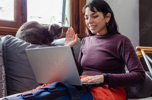 Obraz Young disabled woman having a video call on laptop with her cat.