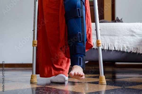 Fototapeta Close up of a young disabled woman using crutches doing rehabilitation exercises.Broken leg.