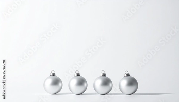 Fototapeta silver Christmas ornaments—three matte and one reflective—arranged in a row on a white surface.