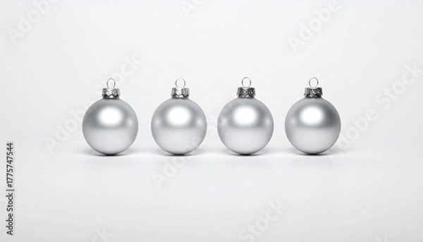 Fototapeta silver Christmas ornaments—three matte and one reflective—arranged in a row on a white surface.