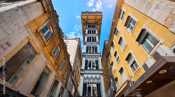 Fototapeta Santa Justa Lift in Lisbon. Famous landmark and entertaining touristic attraction with viewing platform upstairs. Old town among houses at narrow lane.