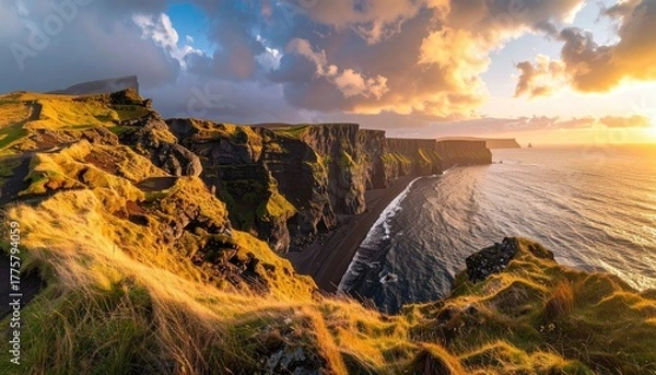 Obraz Dramatic Coastal Cliffs Illuminated by Golden Sunset Light with Ocean Waves and Moody Clouds Overhead