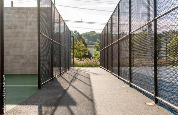 Fototapeta Gated tennis and handball courts. Chain link fence gate in outdoor sport park. Parks and recreation. Abstract park design.
