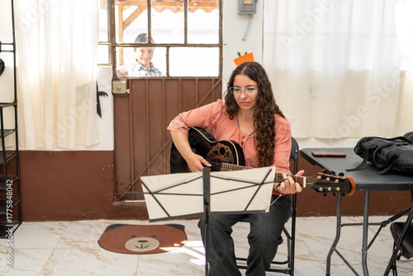 Obraz Guitar teacher preparing the classroom as her young student arrives and knocks on the door, ready for his private lesson. Music education, anticipation, learning environment, tutoring