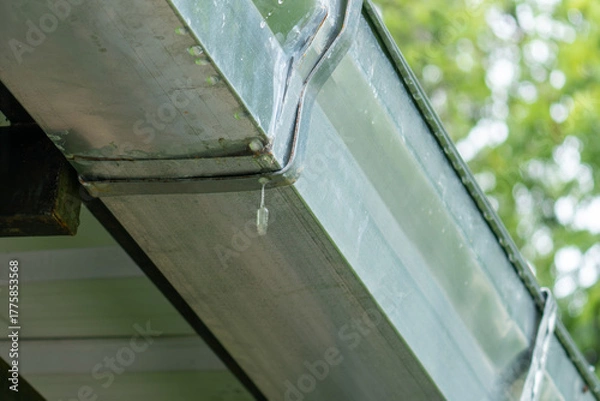 Obraz Leaking galvanized roof gutter joint with water dripping from worn-out seal