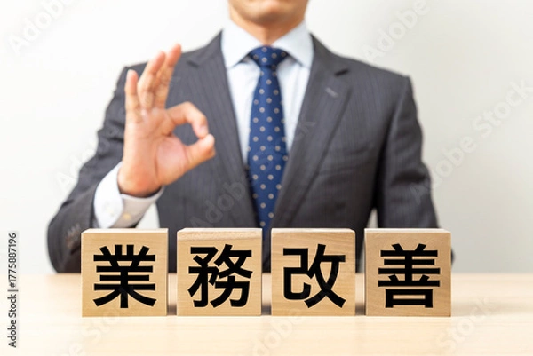 Obraz 「業務改善」と書かれたブロックとOKポーズをするビジネスマン