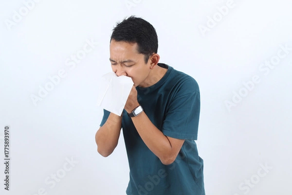 Obraz Sick Asian man sneezing into tissue, flu or allergy symptoms