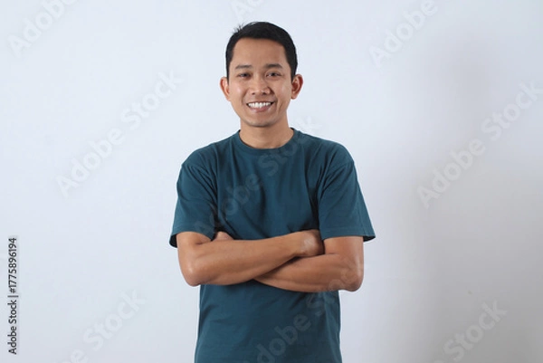 Obraz Confident Asian man smiling with arms crossed on white background.