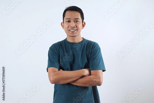 Obraz Confident Asian man smiling with arms crossed on white background.
