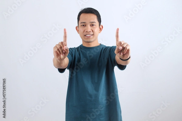 Obraz Happy Asian man pointing up with index fingers, success gesture.