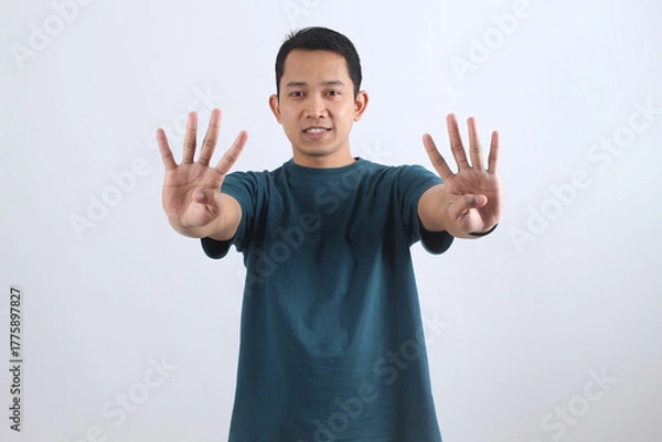 Obraz Asian man showing nine fingers. Hand gesture for the number 9. Isolated portrait.