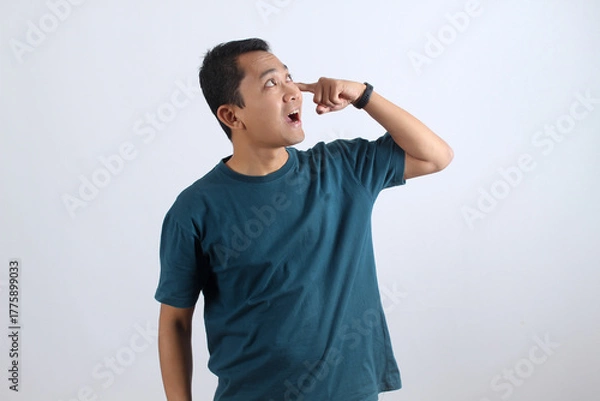 Obraz Funny Asian man has a eureka moment, pointing to his eye with a creative idea