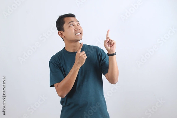 Obraz Inspired Asian man pointing up with an idea on white background.