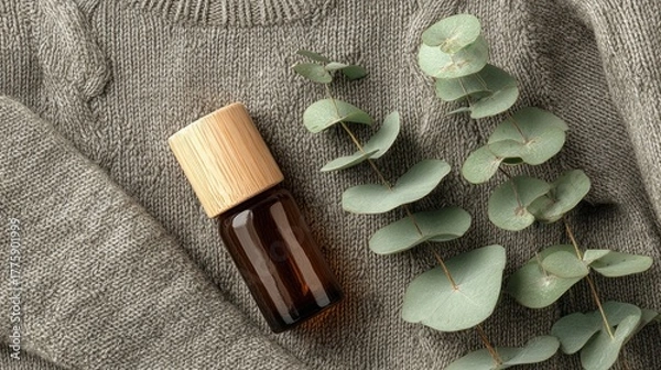 Fototapeta Natural Eucalyptus Leaf and Small Amber Glass Bottle on Soft Grey Fabric