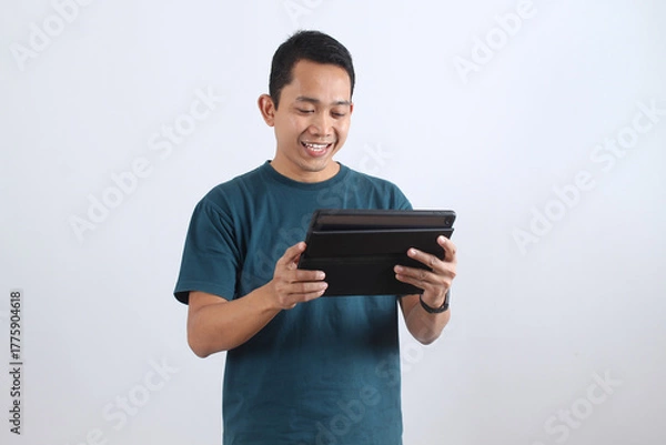 Obraz Smiling Asian man using digital tablet isolated on white background