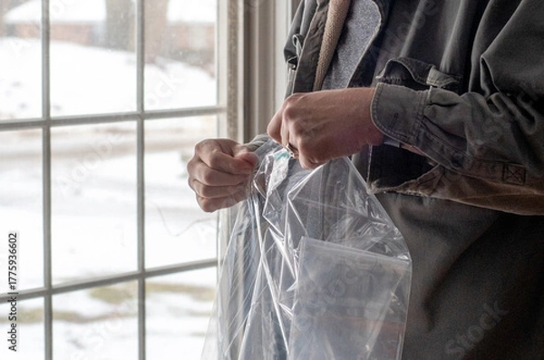 Obraz Hands are Unfolding plastic sheeting for insulation on windows, used to help keep heat in a home during winter 