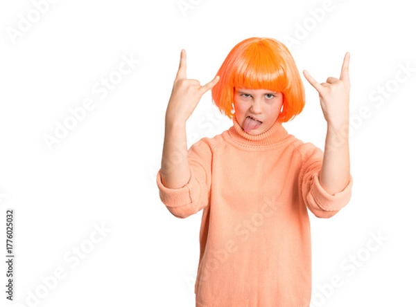 Obraz Playful preteen girl in bright orange wig and sweater showing rock hand signs and sticking out tongue, isolated on white. Perfect for fun, energy, attitude, or youth expression concepts.