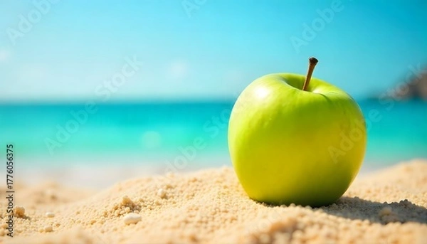 Obraz A vibrant green apple on the beach sand with sea and sky in the background. Perfect mix of freshness, summer, and healthy lifestyle concepts.