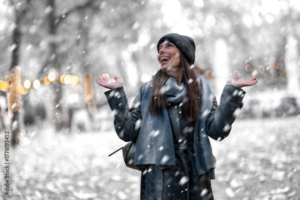 Obraz Cheerful smiling woman standing in the snowfall at the park
